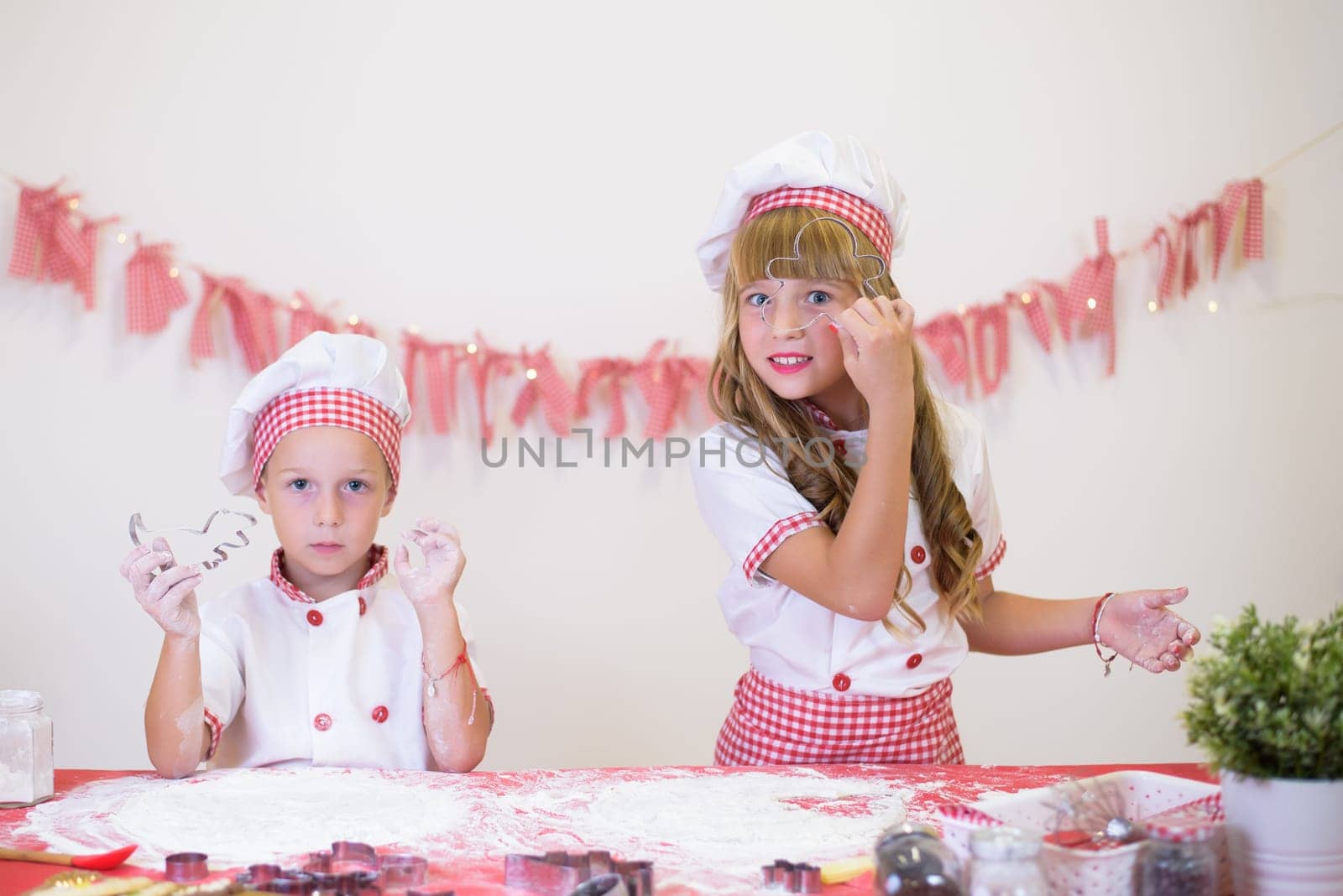 happy smiling children in apron and chef hat cooking cookies with flour, eggs, chocolate and water. Kitchen and family. Happy kids by jcdiazhidalgo