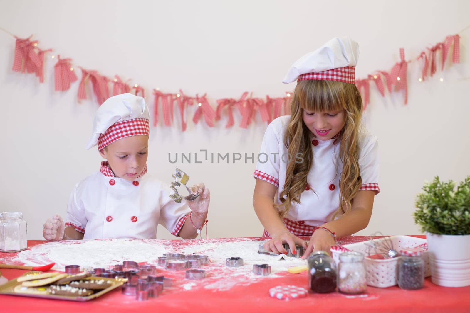 happy smiling children in apron and chef hat cooking cookies with flour, eggs, chocolate and water. Kitchen and family. Happy kids by jcdiazhidalgo