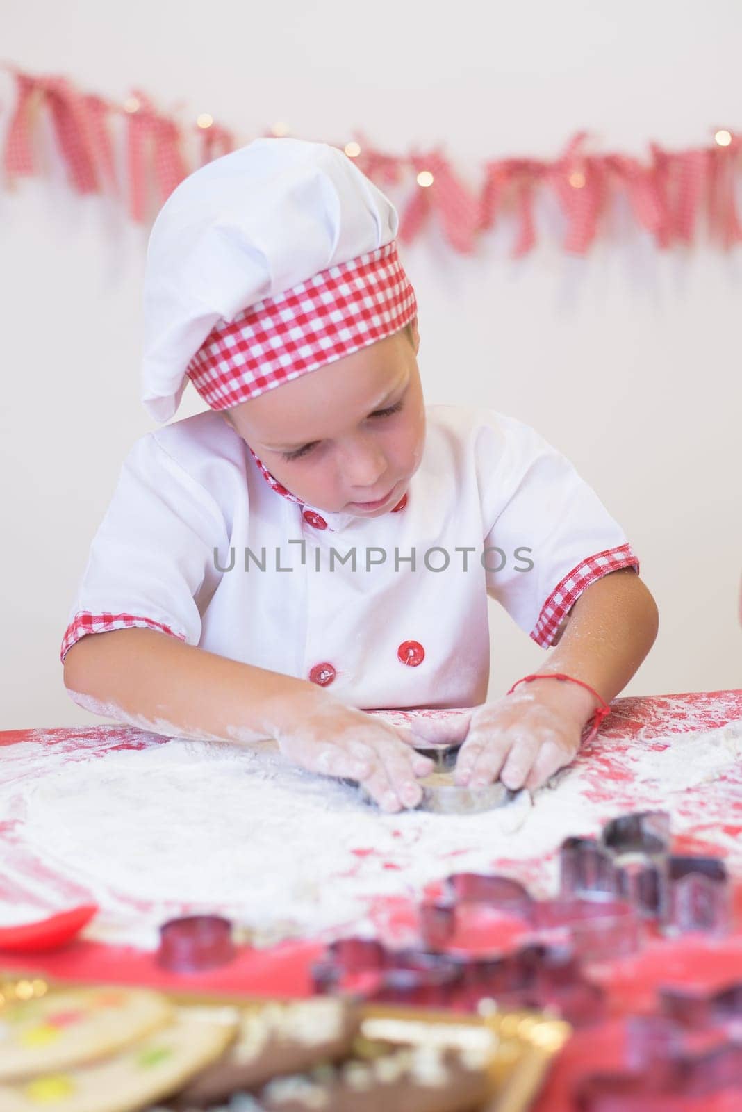 happy smiling child in apron and chef hat cooking cookies with flour, eggs, chocolate and water. Kitchen and family. Happy kids by jcdiazhidalgo