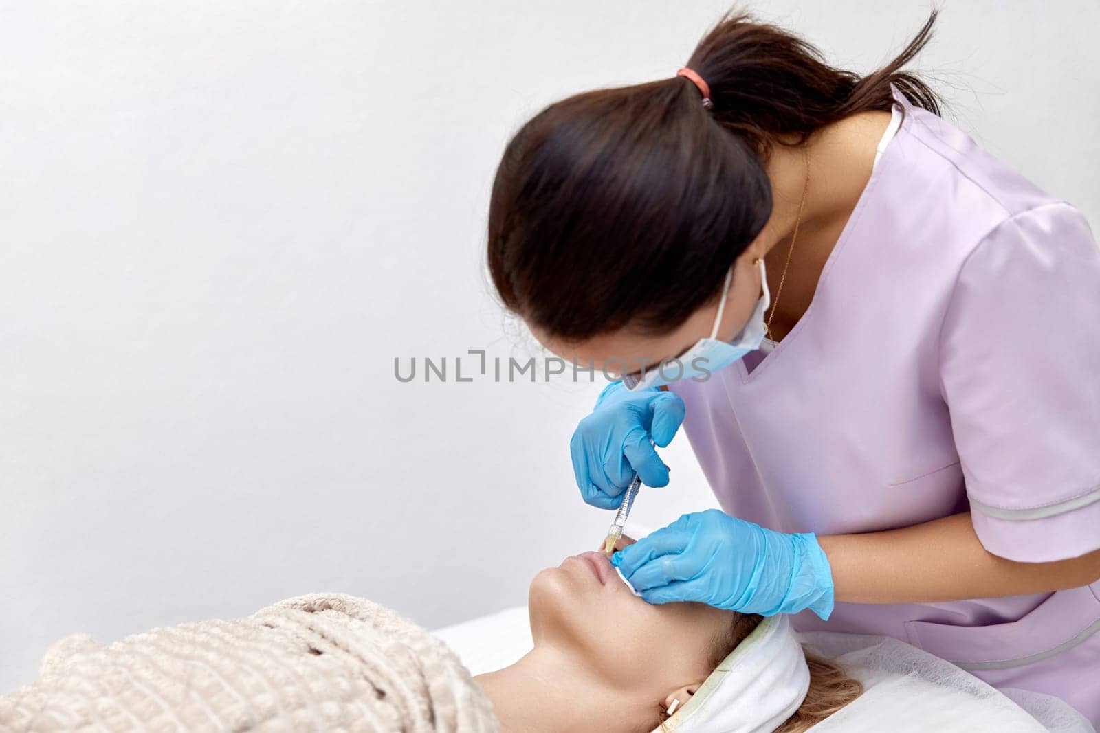 beautician makes injections to enlarge the lips of beautiful woman. procedure lip augmentation