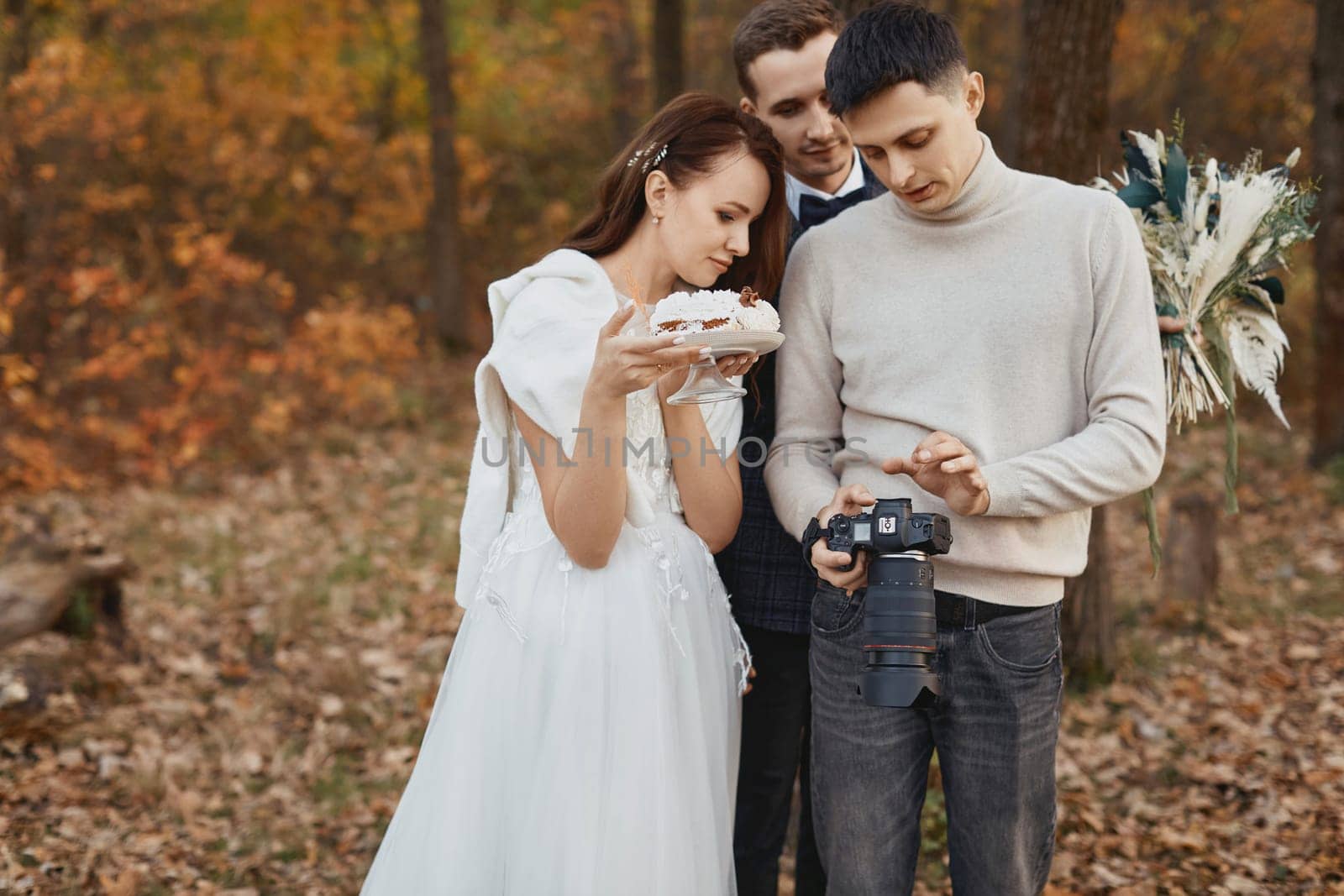 wedding photographer shows just taken photos to wedding couple. bride and groom in nature