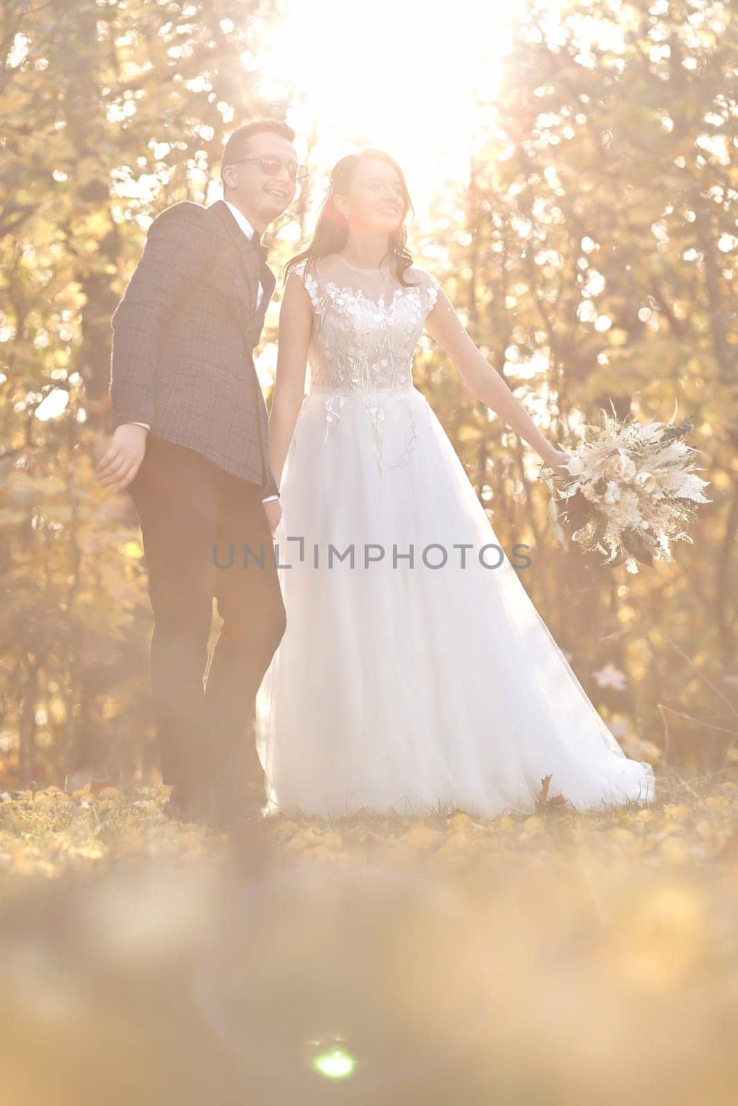 beautiful bride in white wedding dress and groom standing outdoor on natural background in sunny day