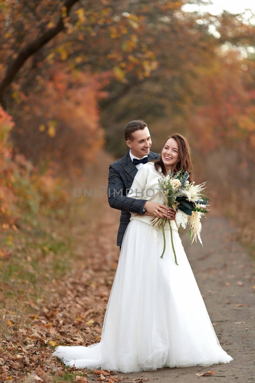 l bride in wedding dress and groom standing in countryside