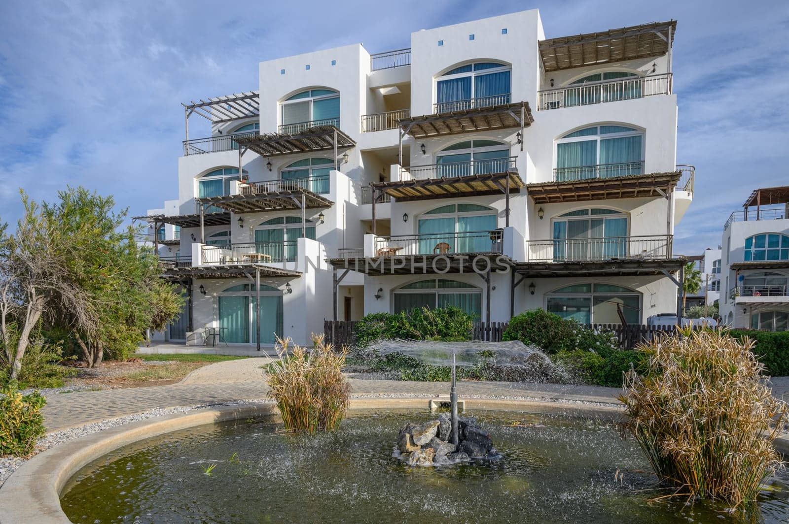 a fountain sprays water against the backdrop of a residential complex near the sea 1 by Mixa74