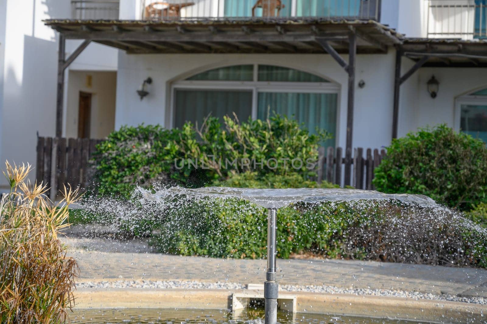 a fountain sprays water against the backdrop of a residential complex near the sea 4