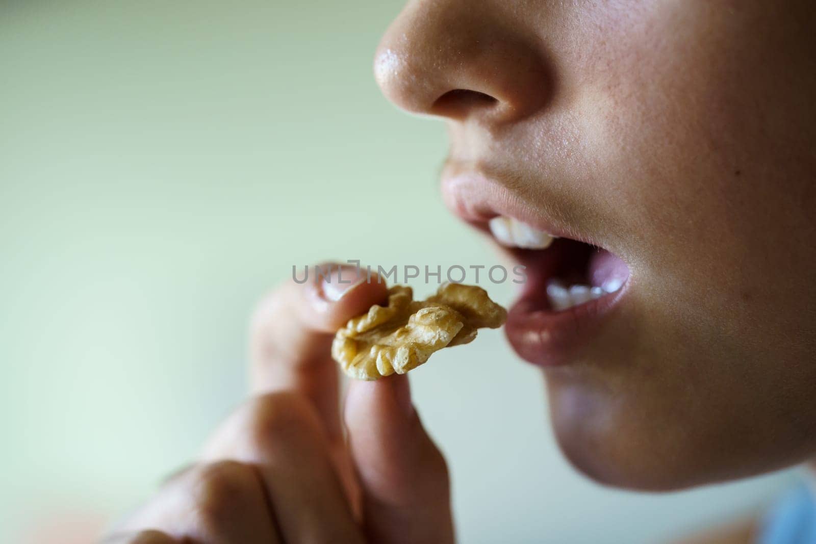 Crop unrecognizable teenage girl with mouth open about to eat delicious walnut at home