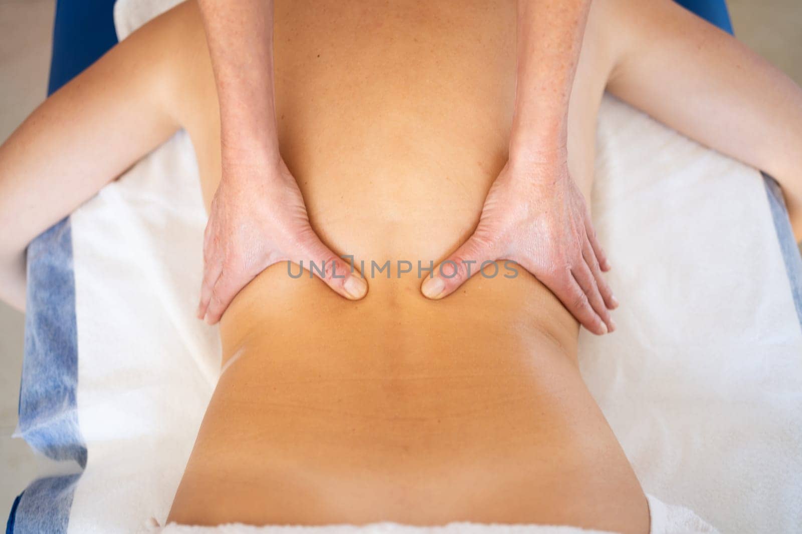 Top view of crop anonymous female massage therapist rubbing back with hands while giving professional treatment to patient in clinic