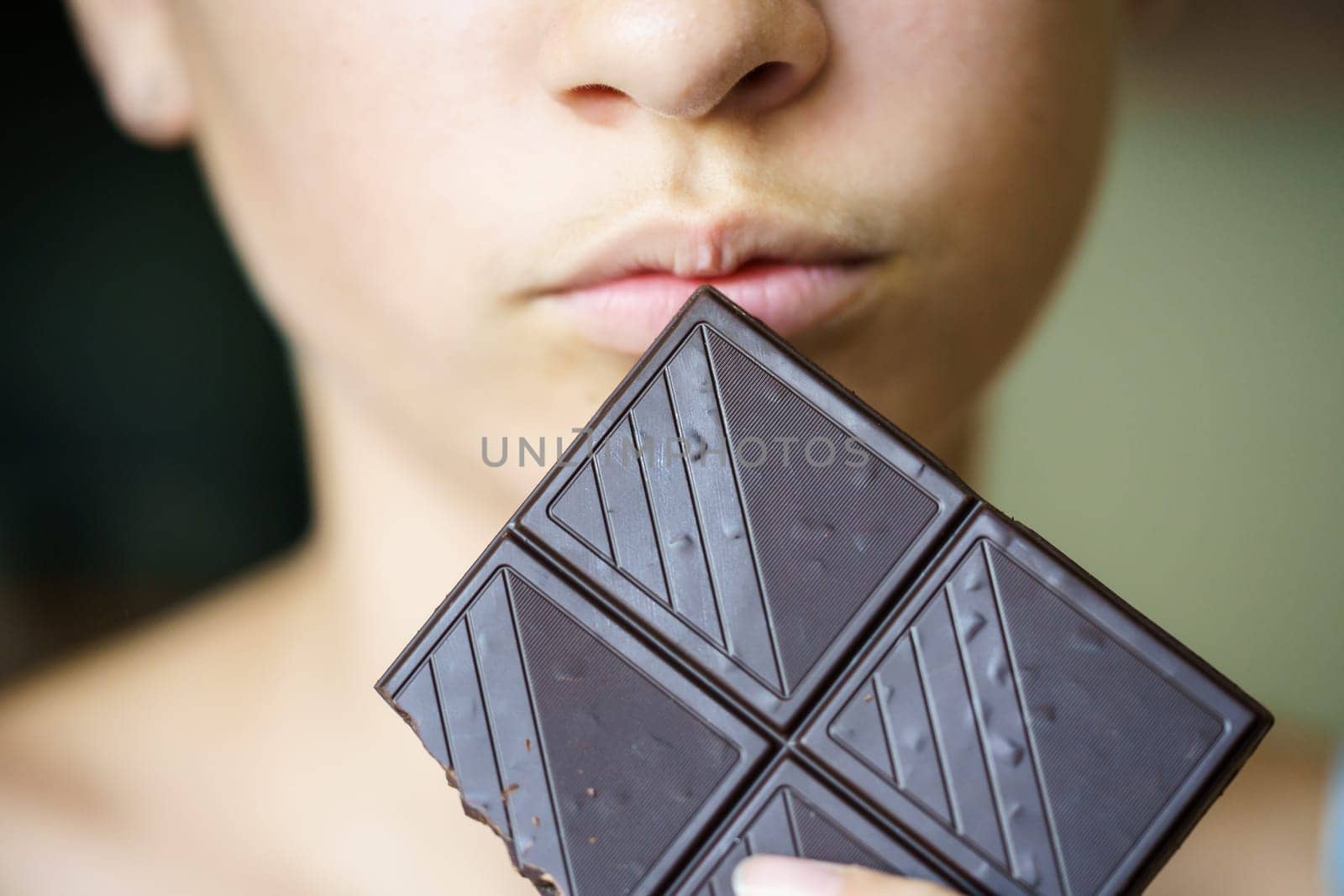 Closeup of crop unrecognizable teenage girl holding chocolate bar at home