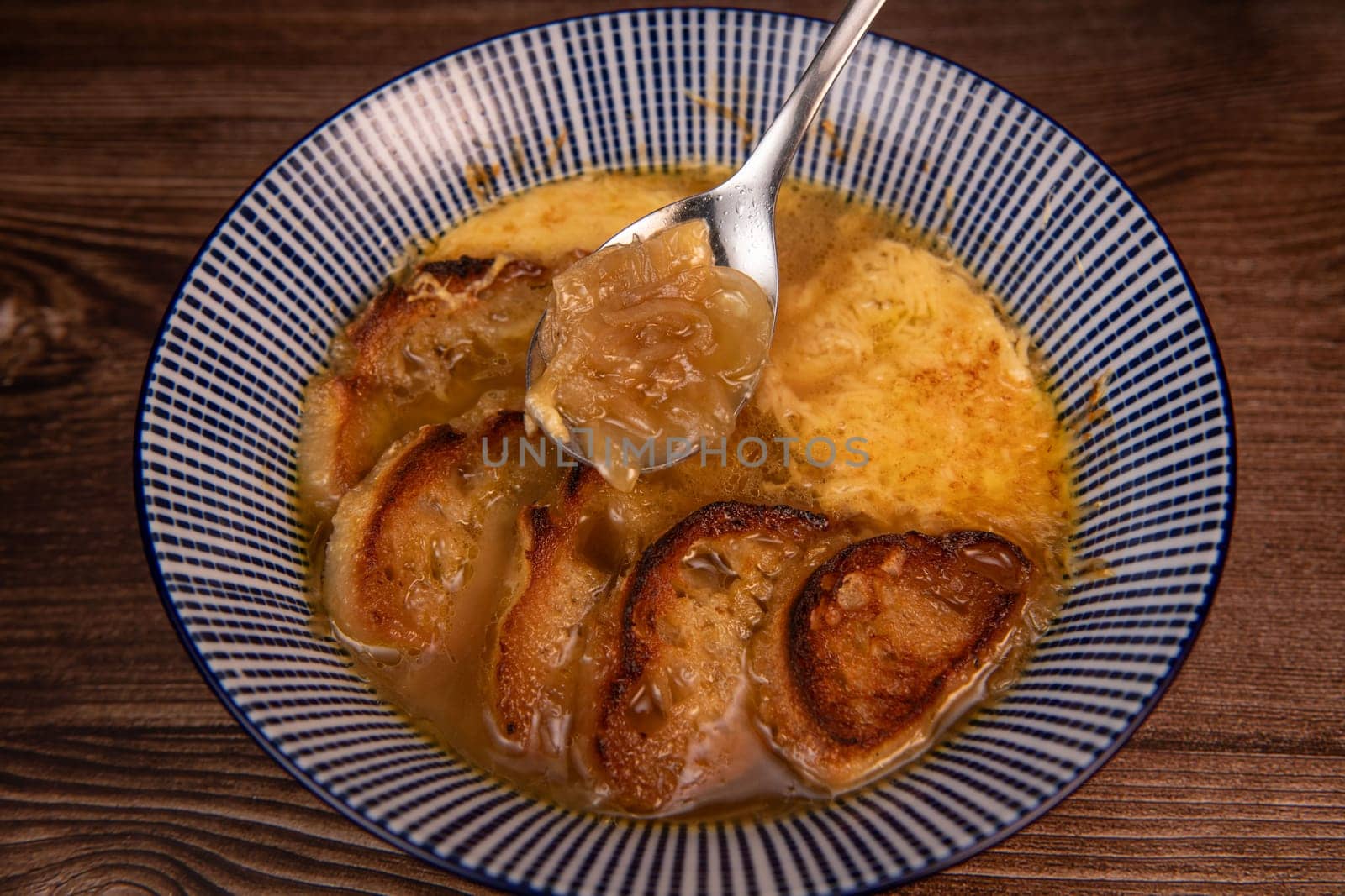 Classic French onion soup baked with cheese croutons sprinkled with fresh thyme, close up view. by FreeProd