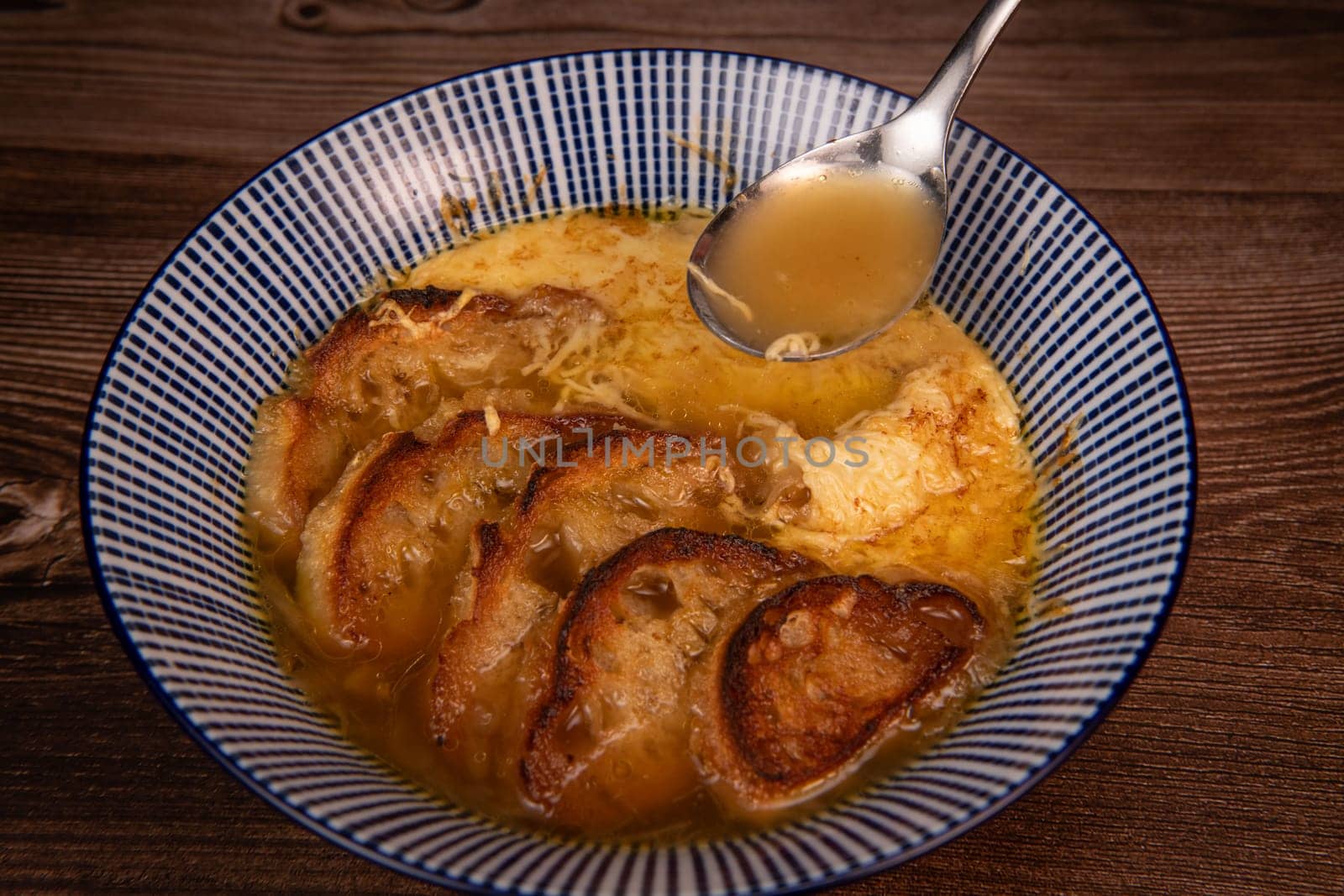 Classic French onion soup baked with cheese croutons sprinkled with fresh thyme, close up view, High quality photo