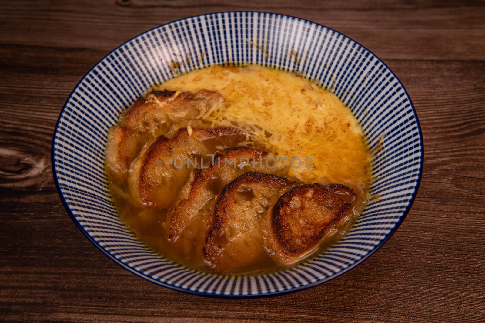 Classic French onion soup baked with cheese croutons sprinkled with fresh thyme, close up view, High quality photo