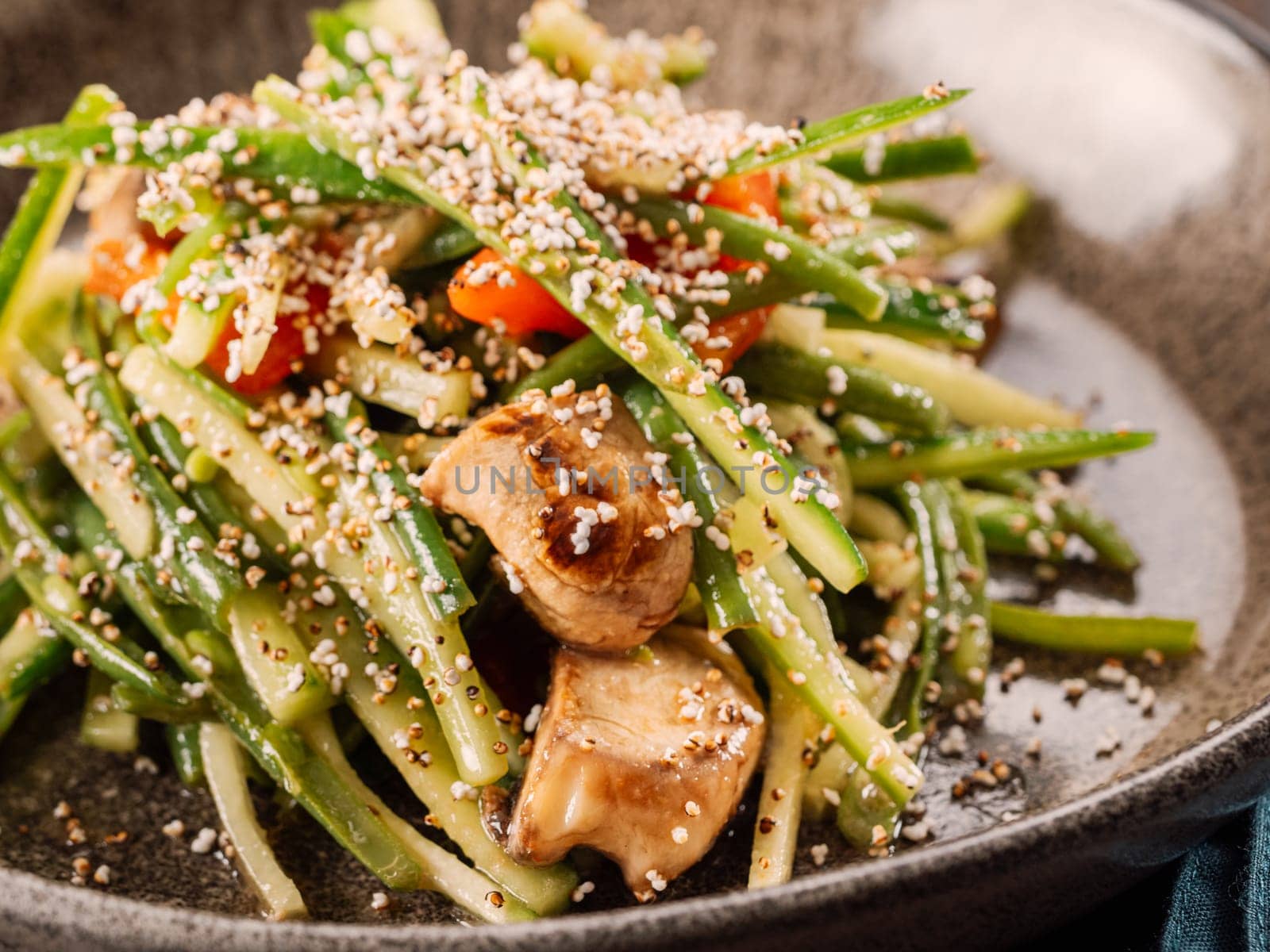 Delicious pork meat salad with cucumber in asian style with amaranth popcorn or popped amaranth (replaceable sesame). Idea salad recipe for healthy food menu. Vibrant bright pork salad with cucumber