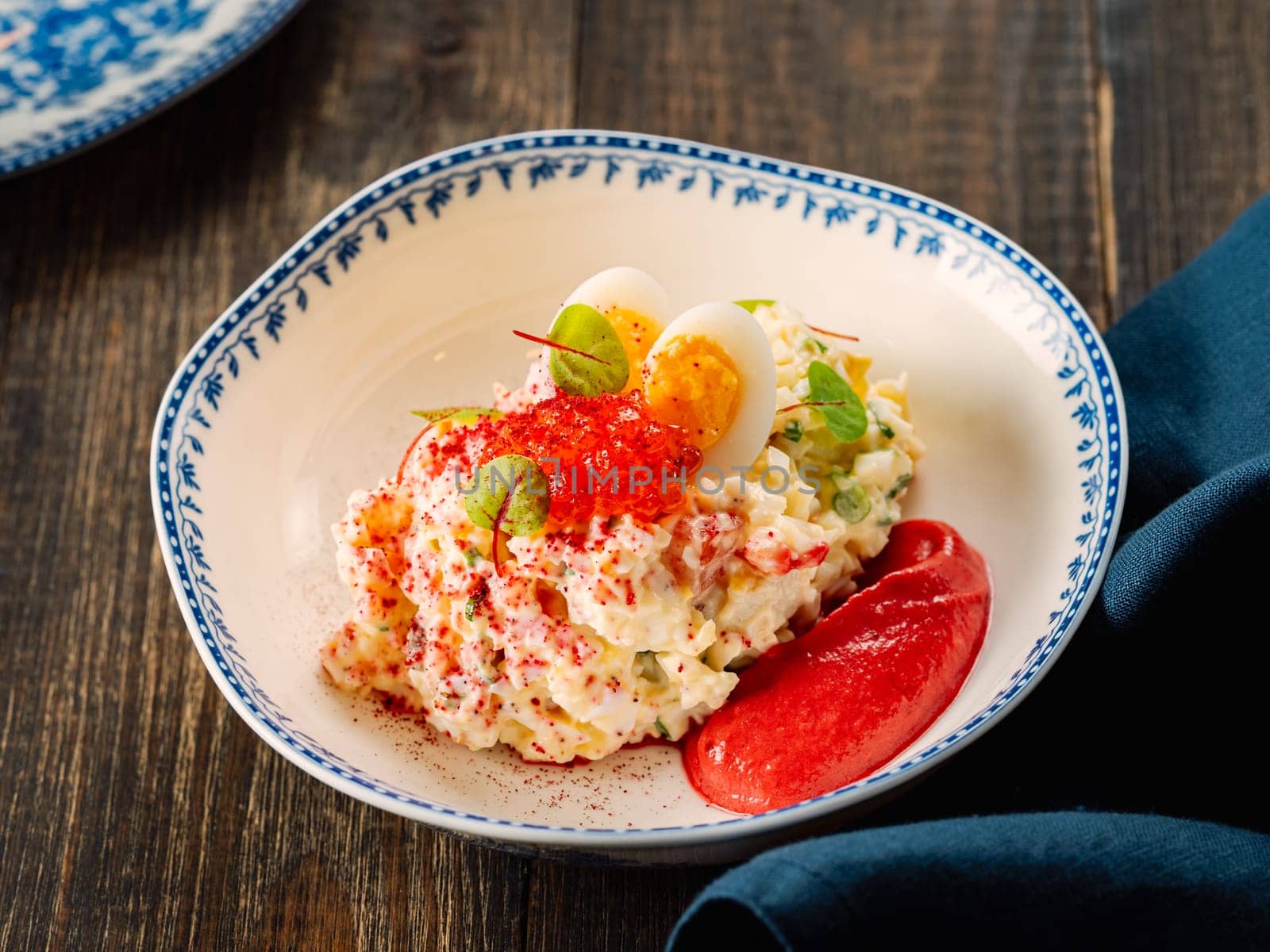 Mayonnaise salad with crab meat, decorated with beetroot mousse in restaurant-style plating. Imitation crab salad with crab sticks or crab meat and eggs in bowl on wooden background