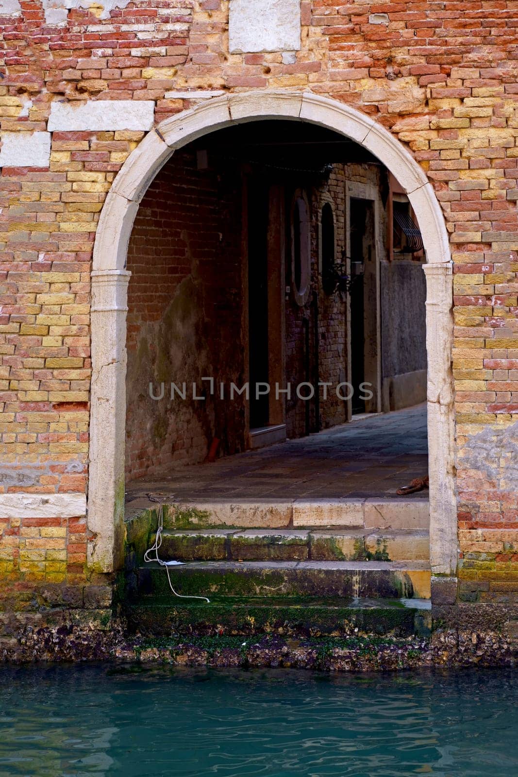 Italy. Close-ups of building facades in Venice. A look at the old scratched arch in the wall near the water in the canal. by aprilphoto