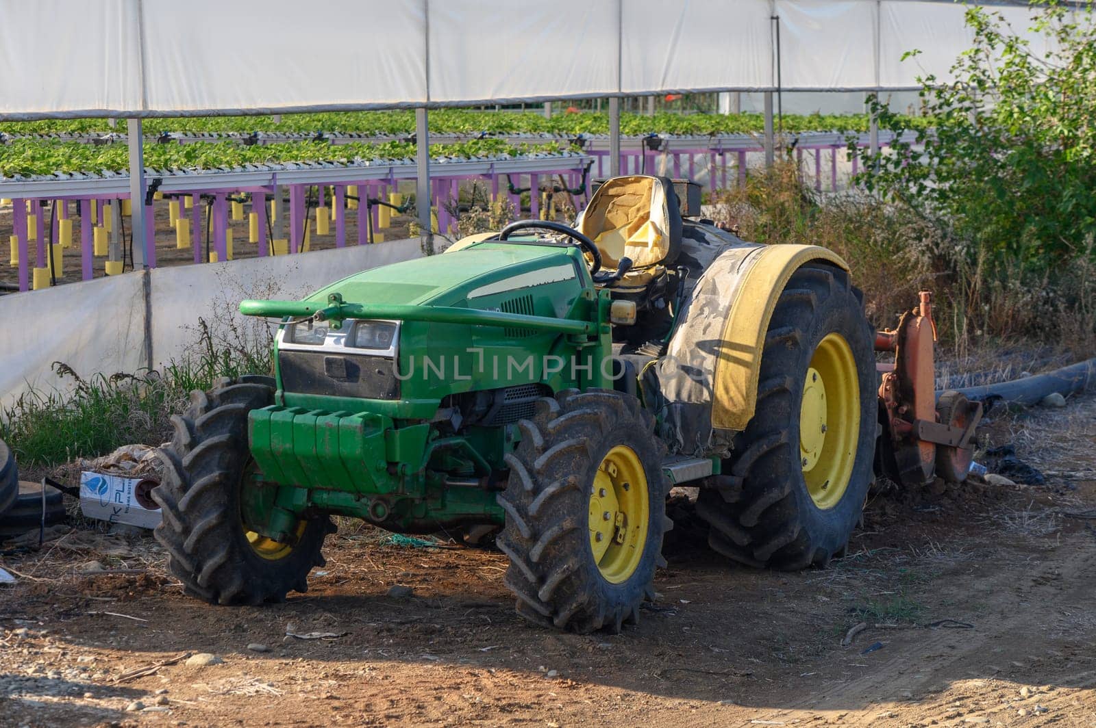 old green tractor near the greenhouse