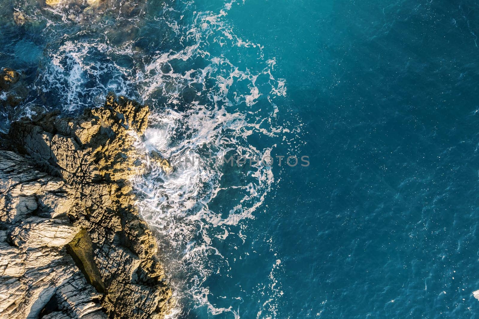 Sea waves crash against a rocky cliff. Drone. High quality photo