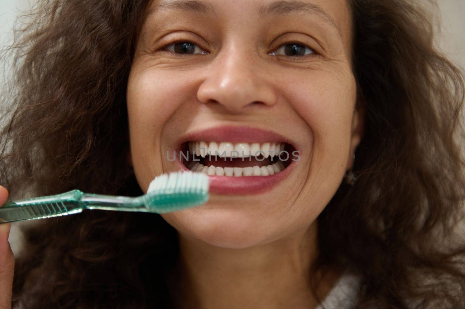 Happy woman smiling with beautiful toothy smile, holding a toothbrush near her face and looking at the camera by artgf