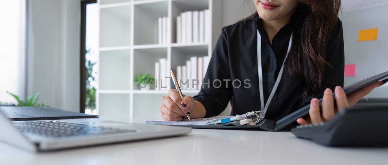 Charming Asian business woman sitting working on laptop in office.