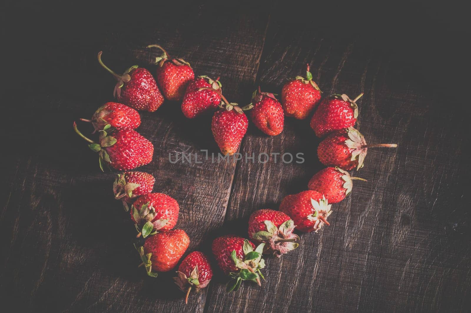 Heart from a strawberry on a wooden background. by Yurii73