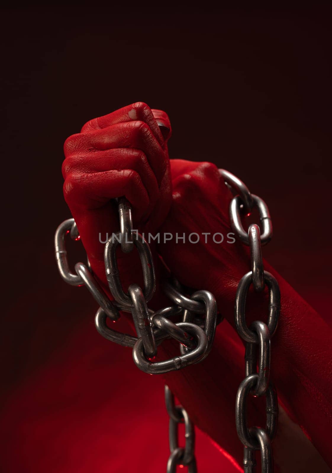 bloodied hands clenched into fists in the shackles of a metal chain symbolize slavery, protest and the struggle for freedom by Rotozey