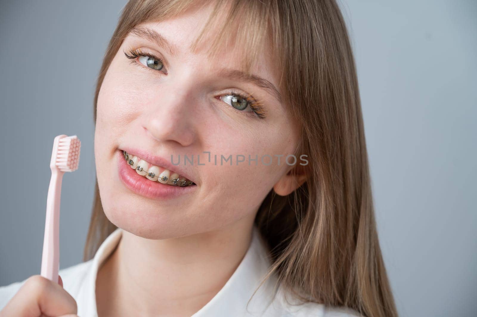 Portrait of a caucasian woman with braces on her teeth holding a toothbrush