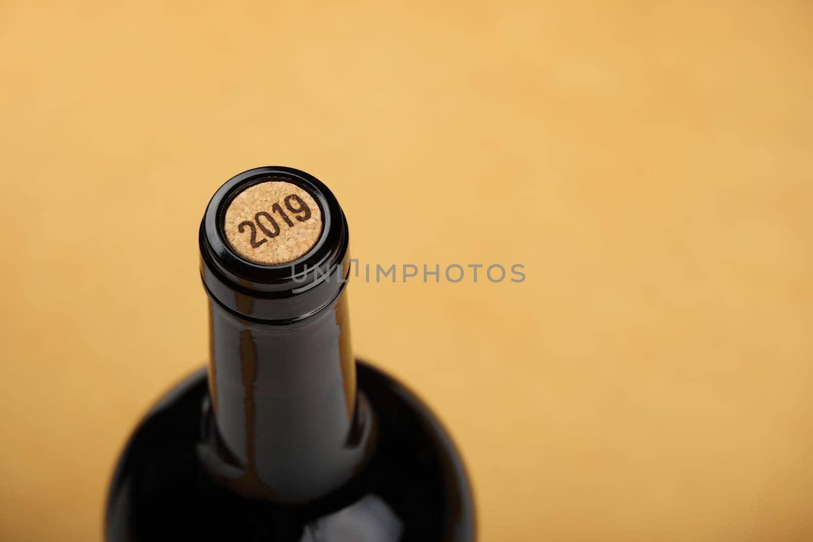 Close up one full unopen bottle of white wine with cork over beige brown paper background with copy space, high angle view, vintage 2019 year