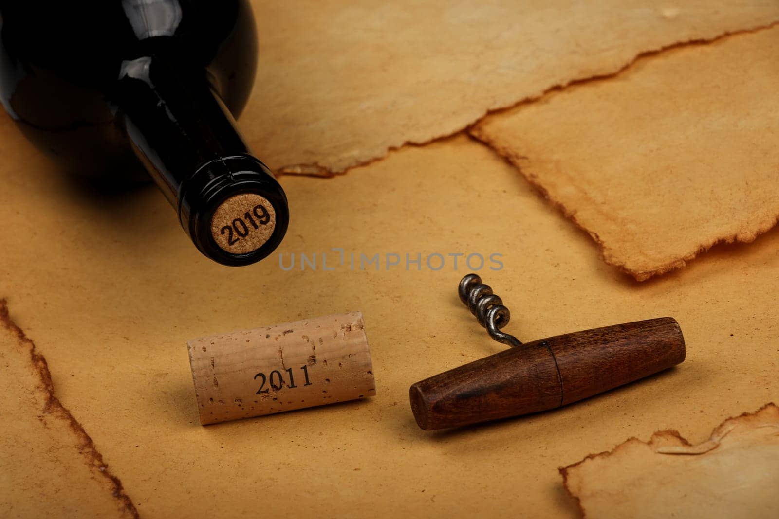 Bottle of wine with cork and opener on brown paper by BreakingTheWalls