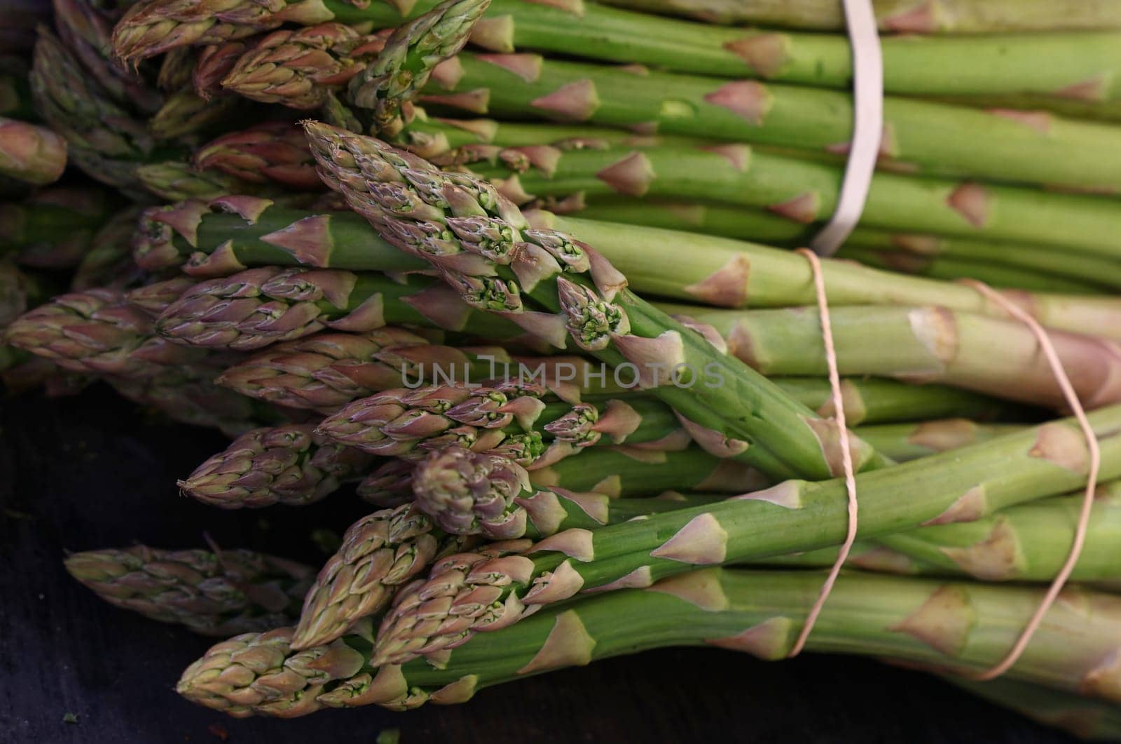 Heap of fresh green asparagus shoots close up by BreakingTheWalls