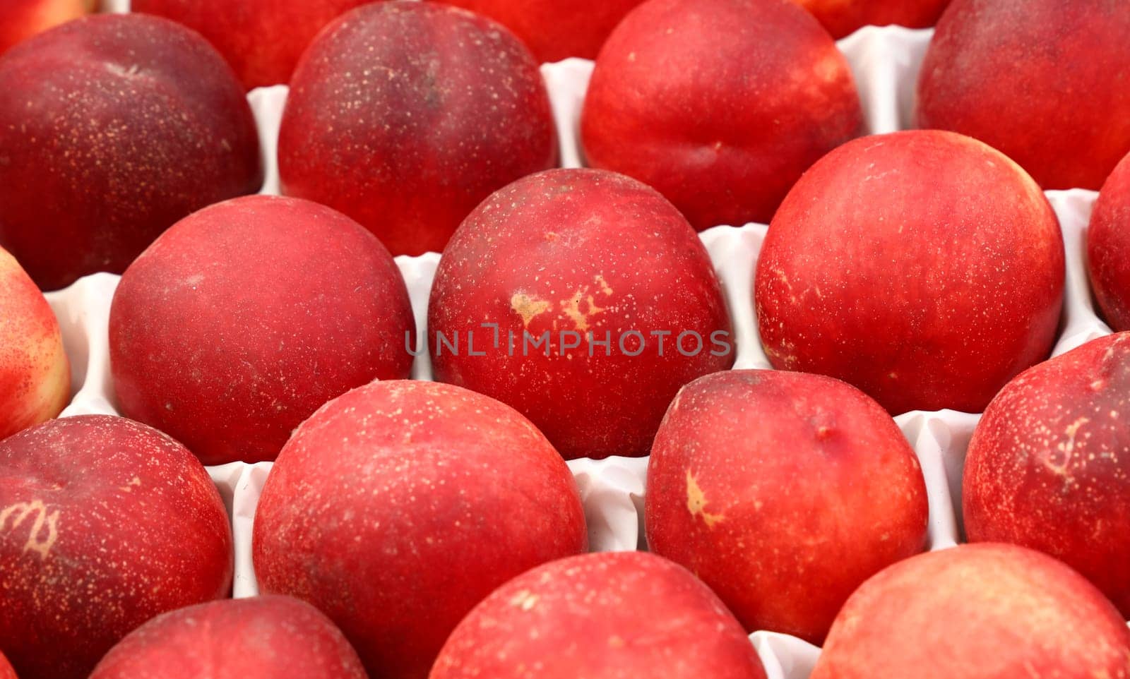 Close up fresh red nectarine peaches at retail display of farmer market, high angle view