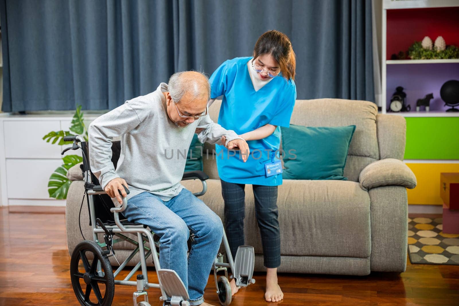 Asian nurse assisting helping senior man patient get up from wheelchair for practice walking by Sorapop