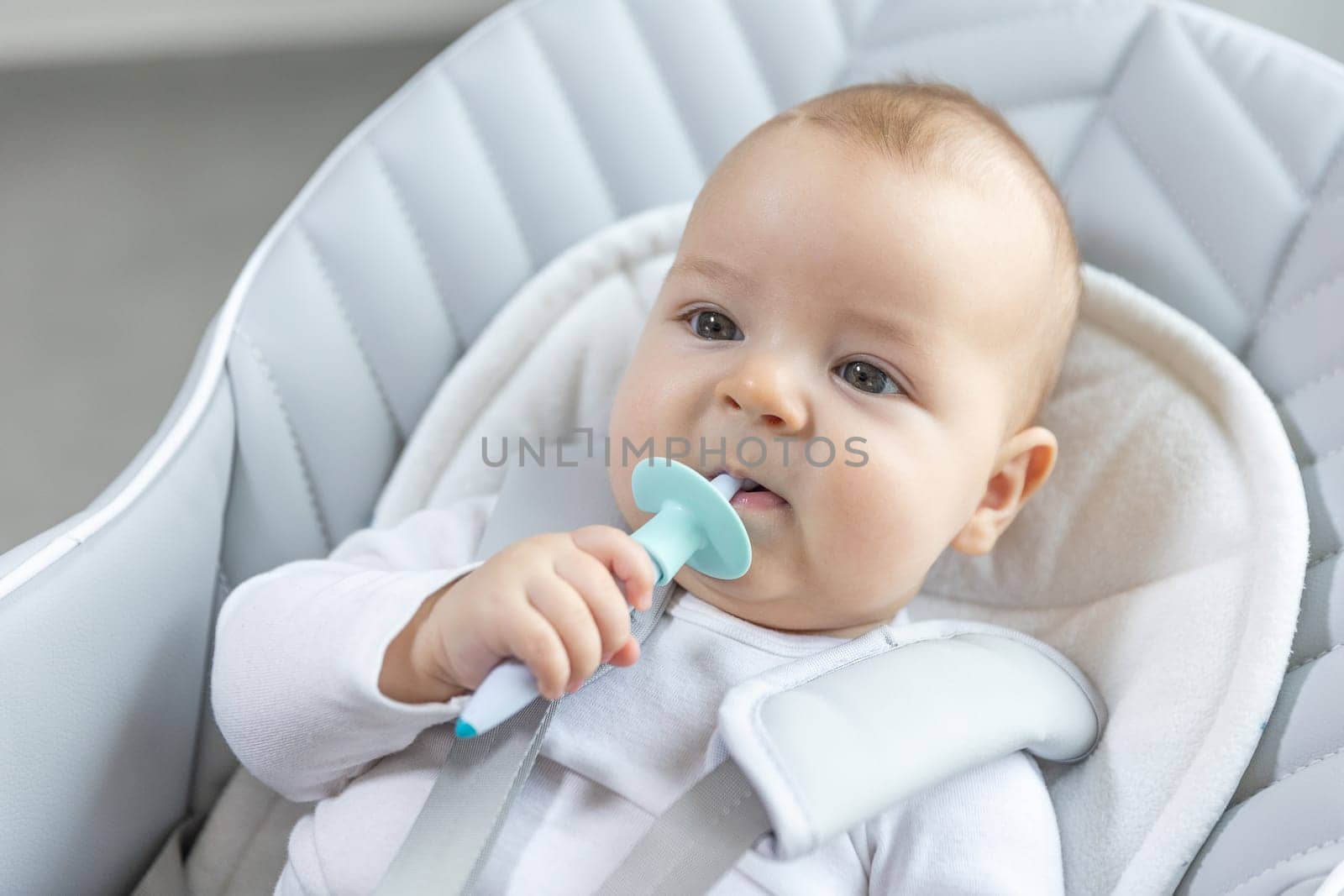 Teeth growth concept, newborn baby with a teether in his mouth for ease the pain, healthcare concept by Kadula