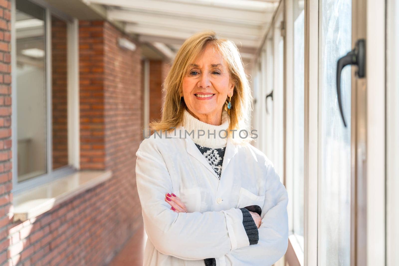 Proud mature female doctor smiling at camera with arms crossed in the hospital