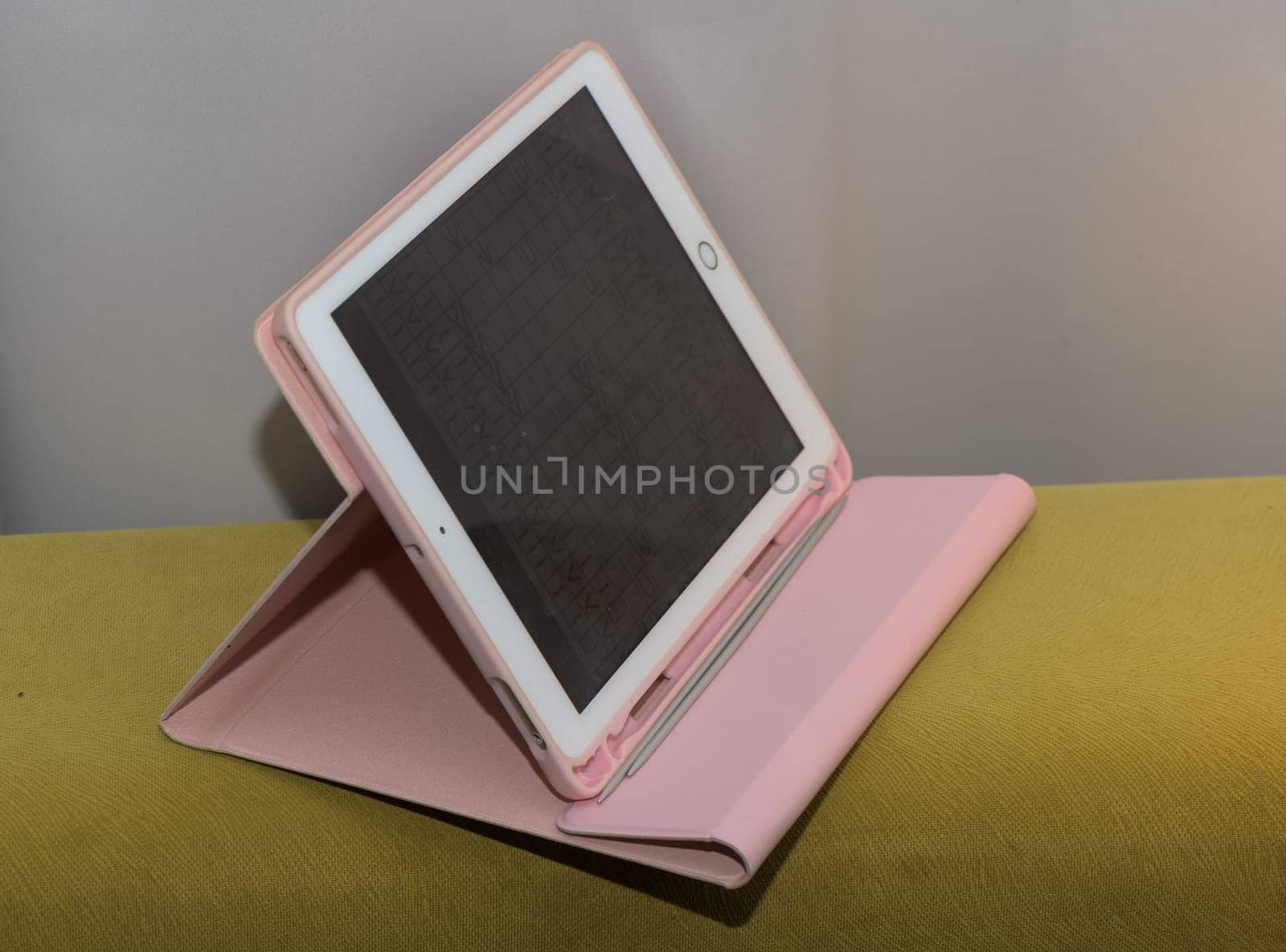 tablet in a pink case on a yellow sofa