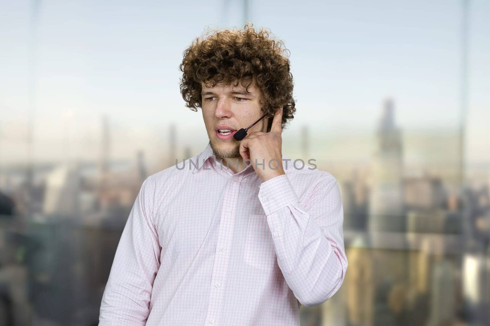 Young attractive and confident successful man talking in microphone. Speaking at corporate business coaching. Blurred cityscape in the background.