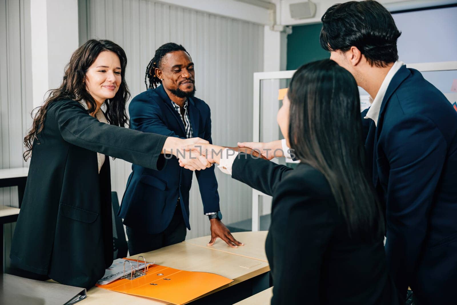 Professionals in an office seal a deal with a handshake, symbolizing success. Executives, lawyers, and managers collaborate to celebrate their partnership after a meeting. Teamwork