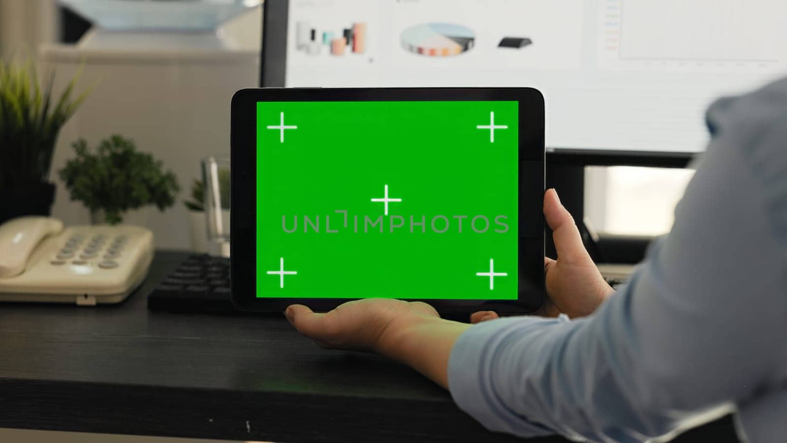 Woman checking greenscreen on tablet in creative agency coworking space, looking at chromakey display with isolated mockup on mobile gadget layout. Employee holding mockup device.