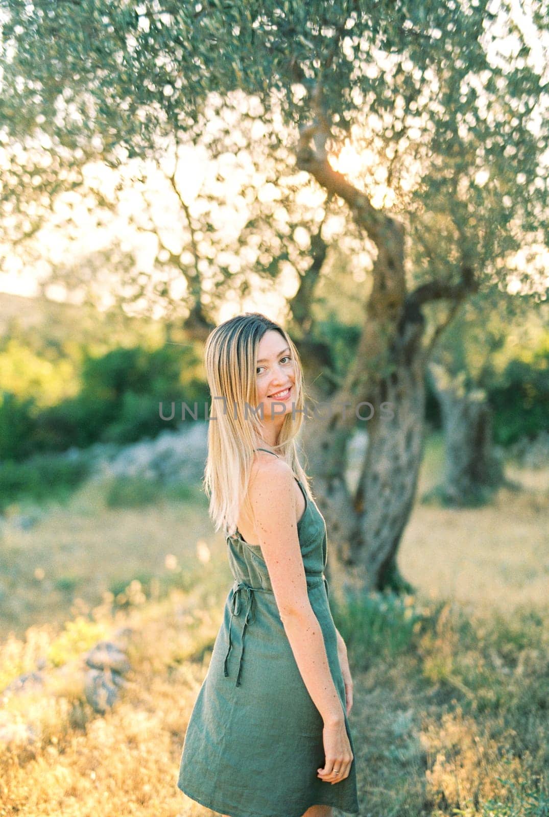 Smiling girl walks in the park, turning back. High quality photo