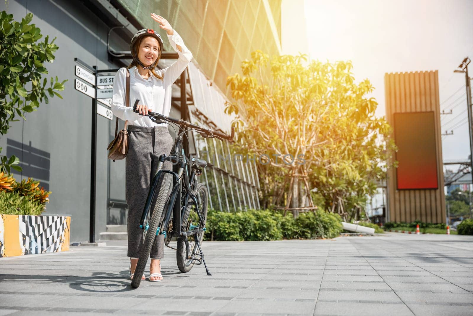 Amid the city hustle and bustle a girl shields herself from the sun on her bike commute capturing a cheerful portrait in a sunny urban environment. This is outdoor relaxation at its best.