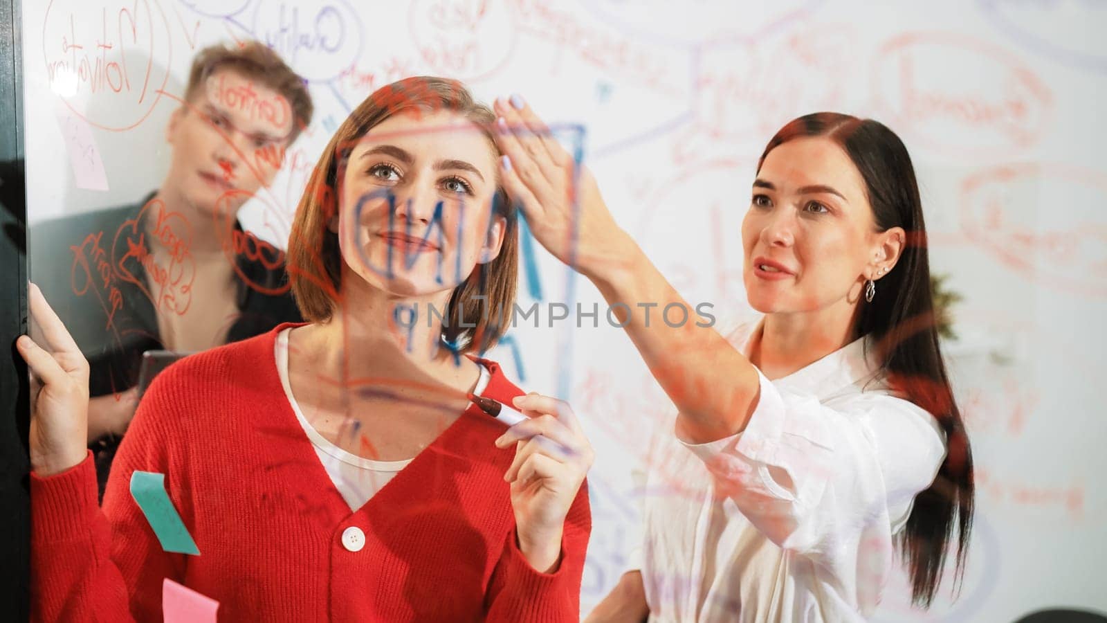 Professional business team brainstorming and working together about marketing project. Female caucasian leader writing idea on stick note while coworker present her idea confidently. Immaculate.