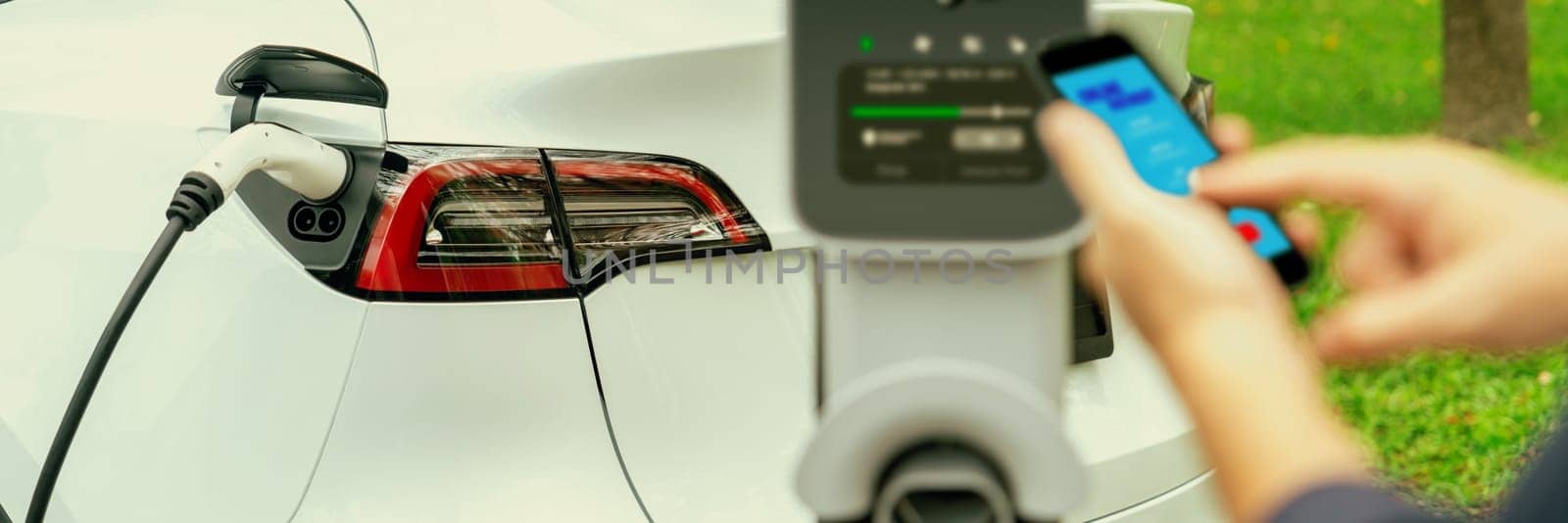 Man using smartphone to pay for electric car charging. Exalt by biancoblue