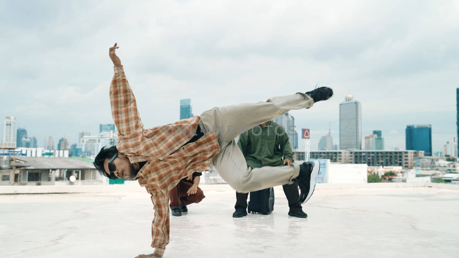 Professional hispanic break dancer practice B boy dance while multicultural friends at roof top. Young modern dancing group doing hip hop movement. Style,fashion,action. Outdoor sport 2024. Endeavor.