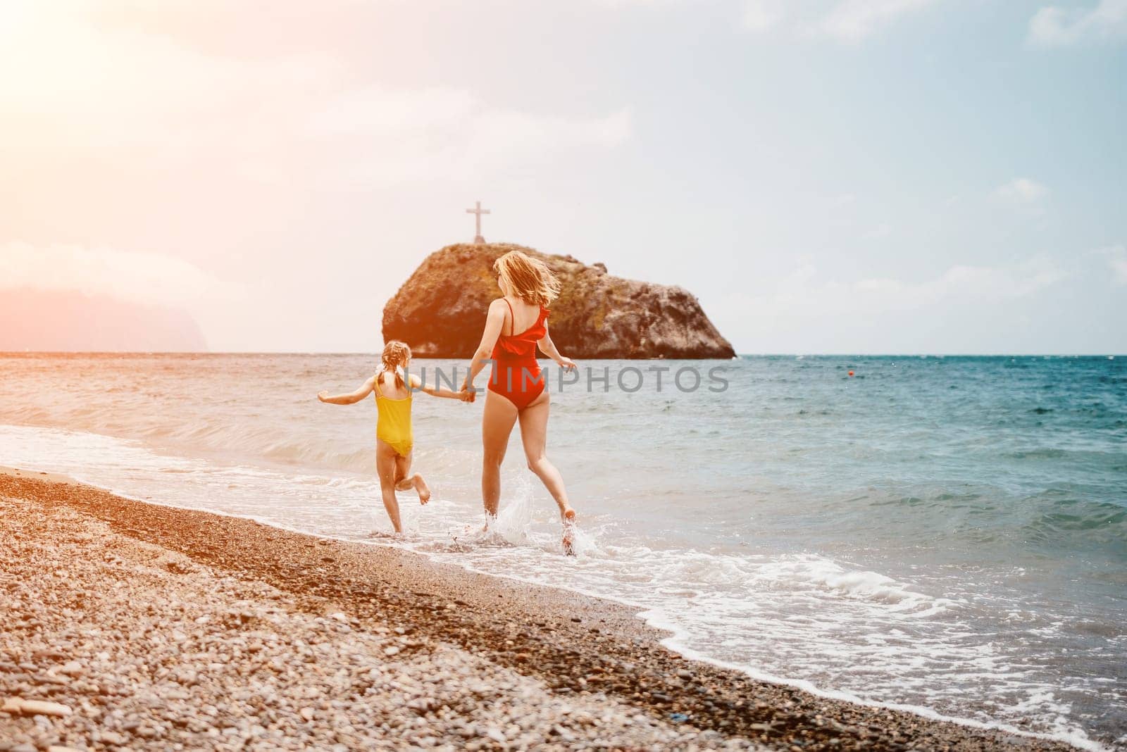 Happy loving family mother and daughter having fun together on the beach. Mum playing with her kid in holiday vacation next to the ocean - Family lifestyle and love concept by panophotograph