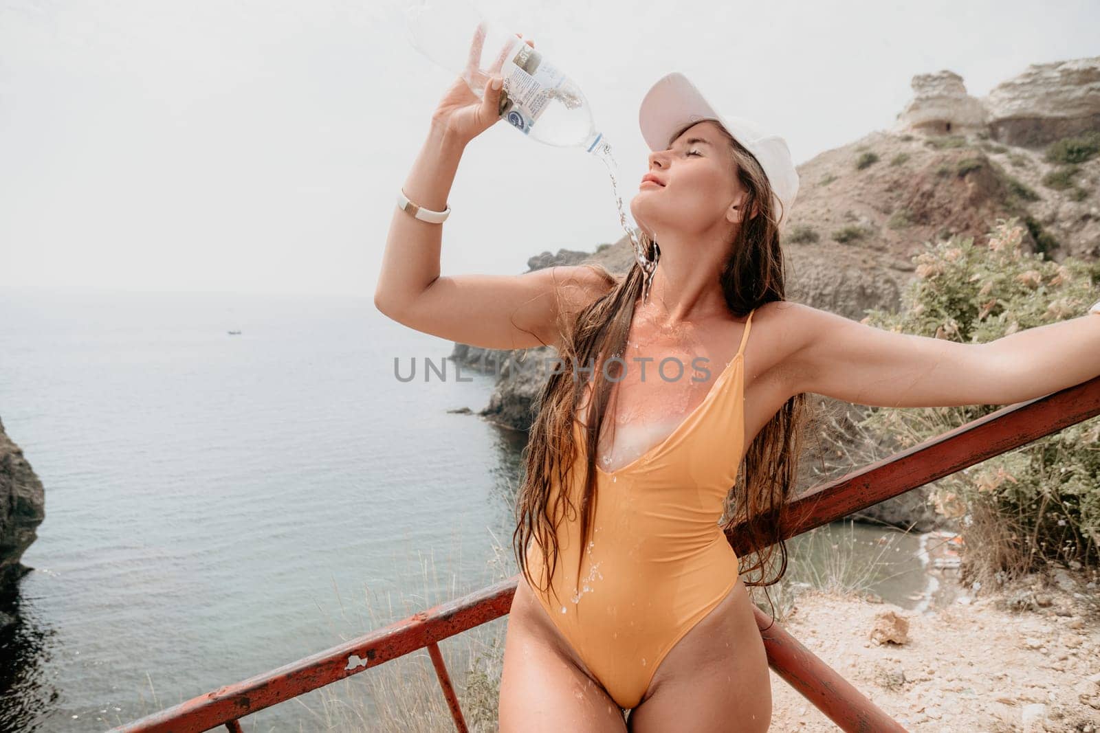 Woman travel sea. Happy tourist enjoy taking picture outdoors for memories. Woman traveler drinks water at the edge of the cliff on the sea bay of mountains, sharing travel adventure journey by panophotograph