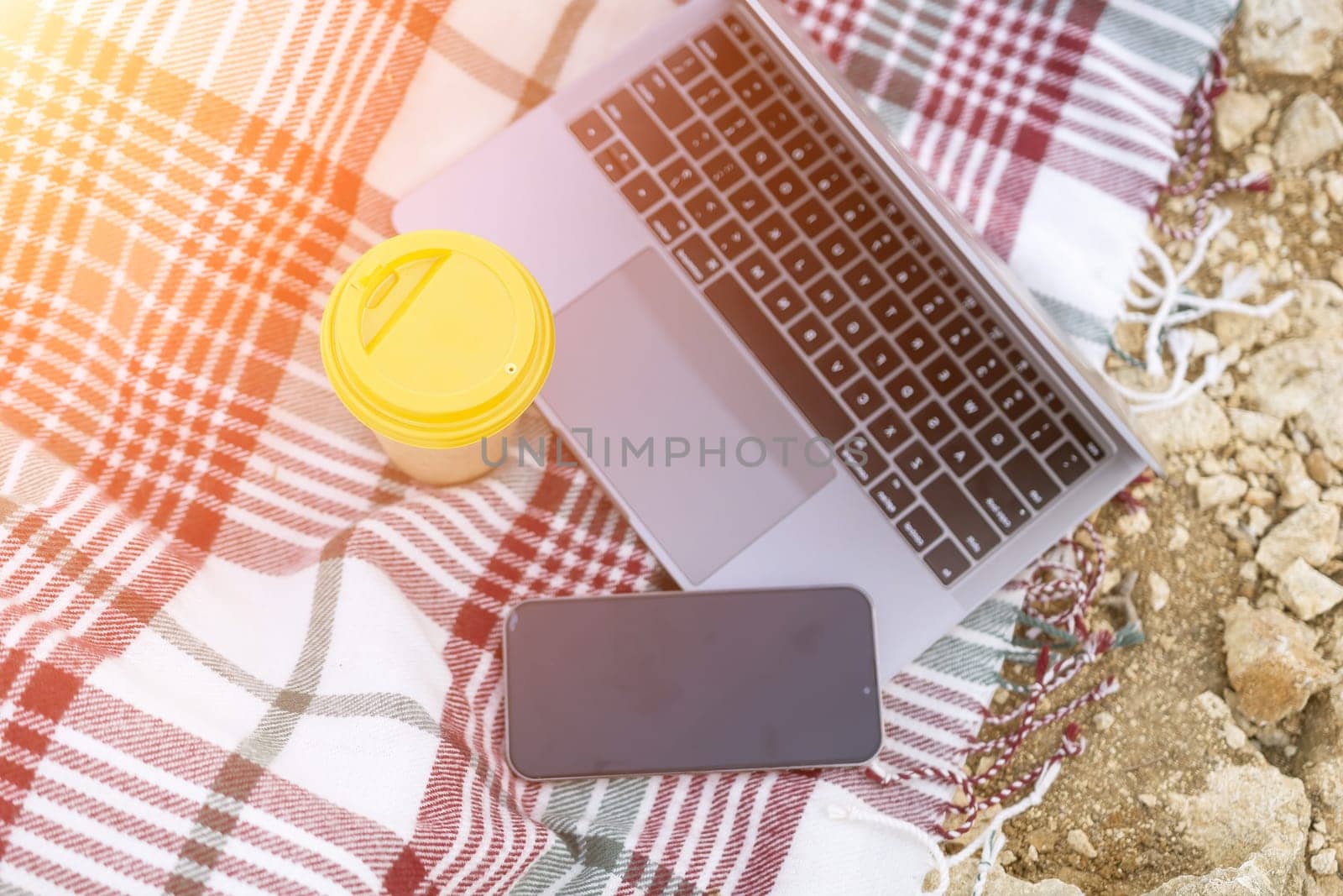 Laptop on blanket with ocean view. Illustrating serene outdoor laptop use. Freelancer enjoying their time outdoors while working or browsing the internet. by Matiunina
