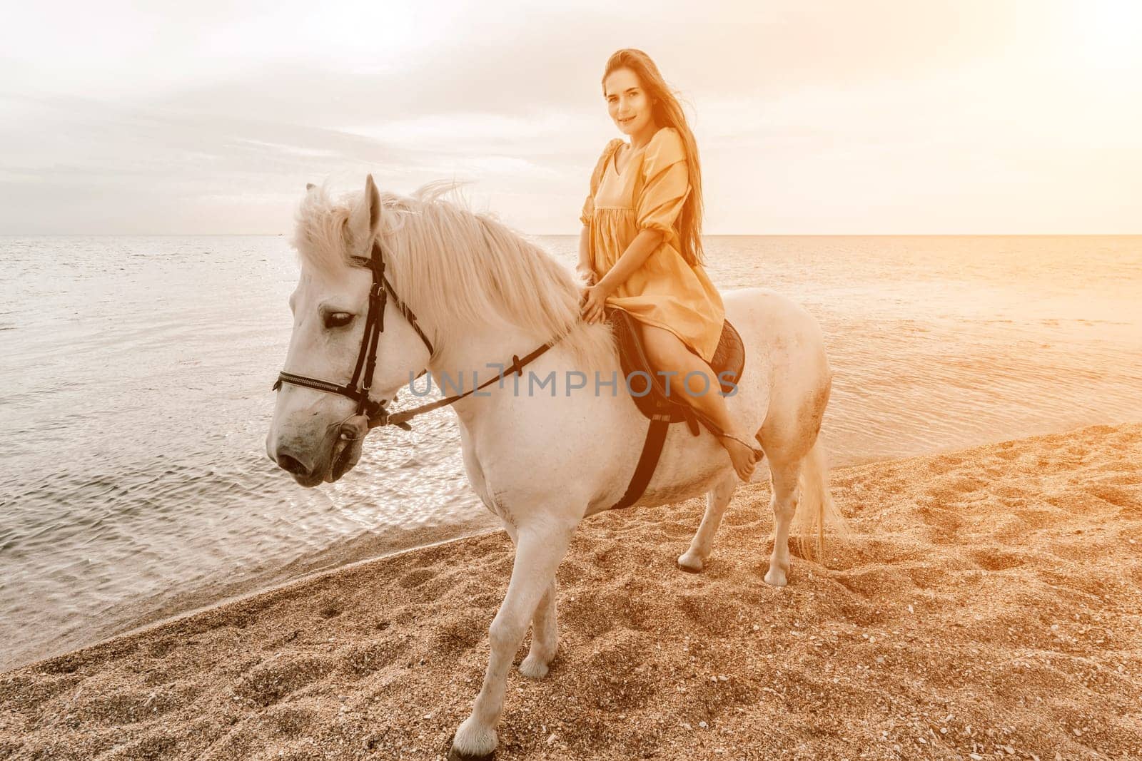 A white horse and a woman in a dress stand on a beach, with the sky and sea creating a picturesque backdrop for the scene