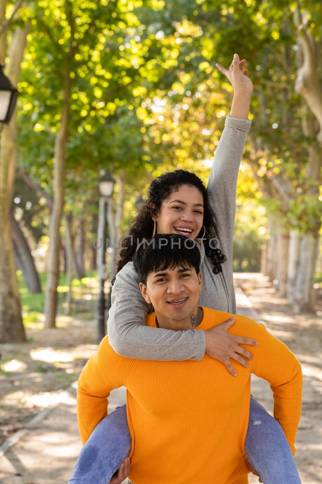 Young couple having fun at a park. Successful woman in piggyback ride with positive mood.