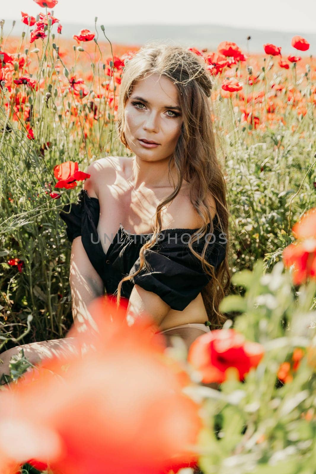 Woman poppies field. portrait of a happy woman with long hair in a poppy field and enjoying the beauty of nature in a warm summer day