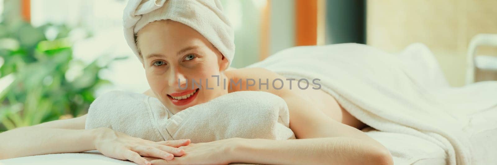 Beautiful young woman relaxes on a spa bed surrounded by nature. ready for a body massage. Attractive female in white towel lying peacefully during waiting for body massage. Close up. Tranquility