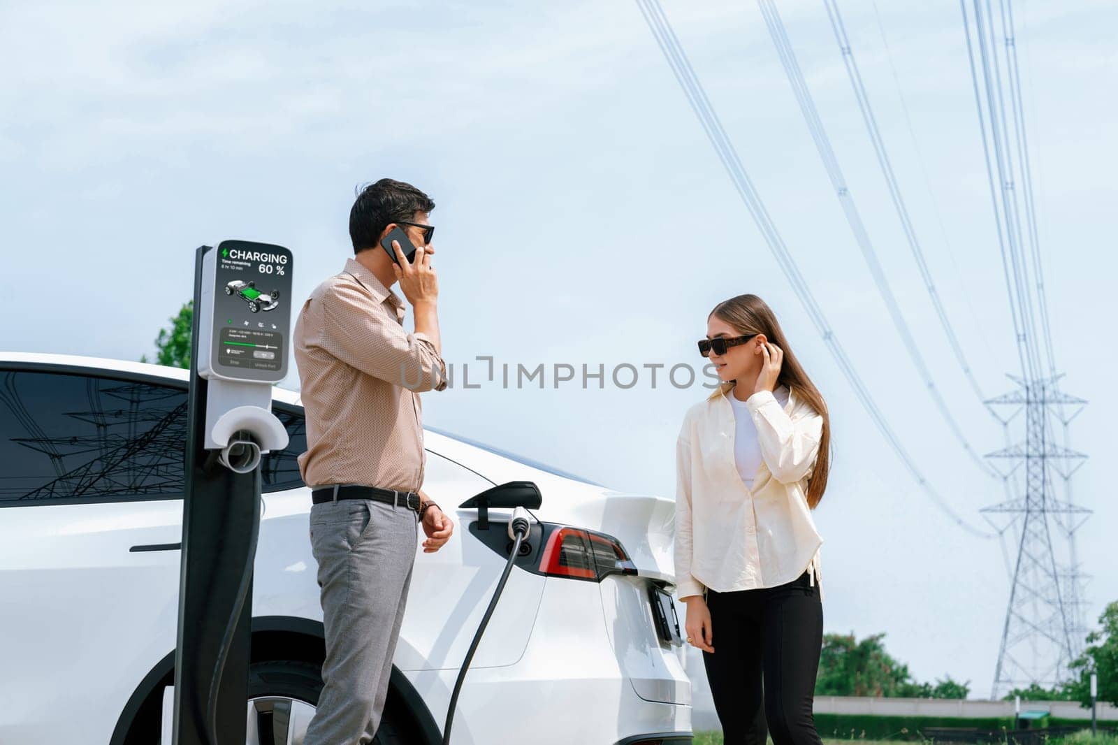 Couple recharge EV car battery at charging station. Expedient by biancoblue