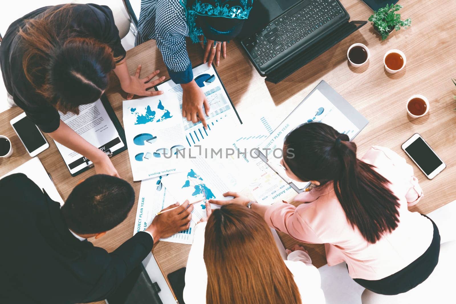 Top view of businessman executive in group meeting with other businessmen and businesswomen in modern office with laptop computer, coffee and document on table. People corporate business team uds